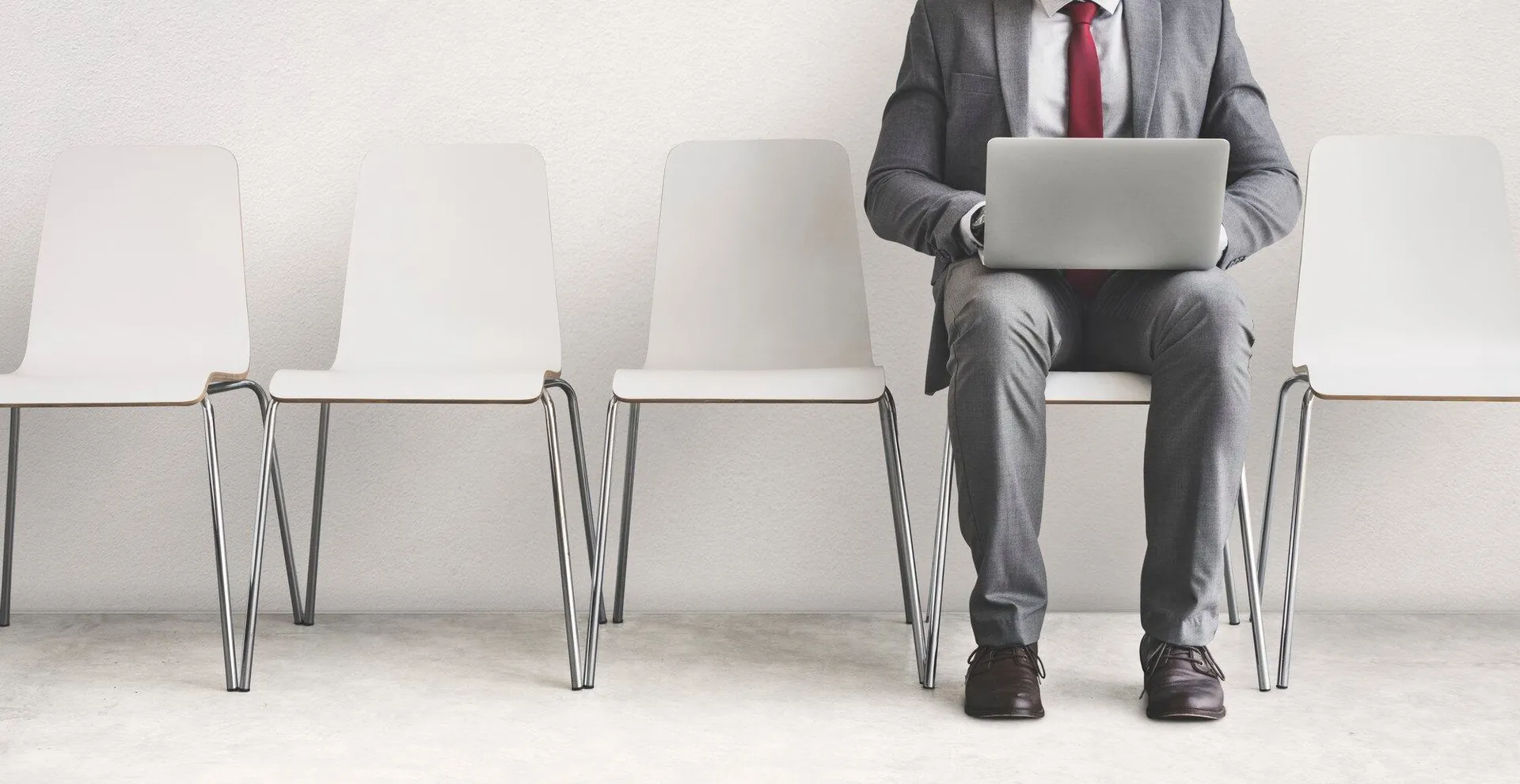 Candidate working on a laptop in a row of waiting-room chairs