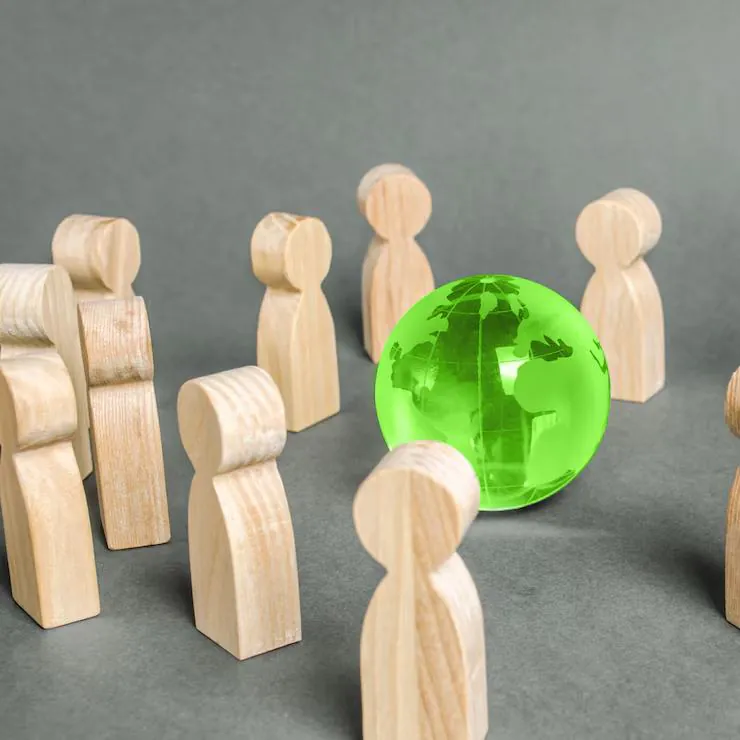 Wooden figures standing around a green glass globe